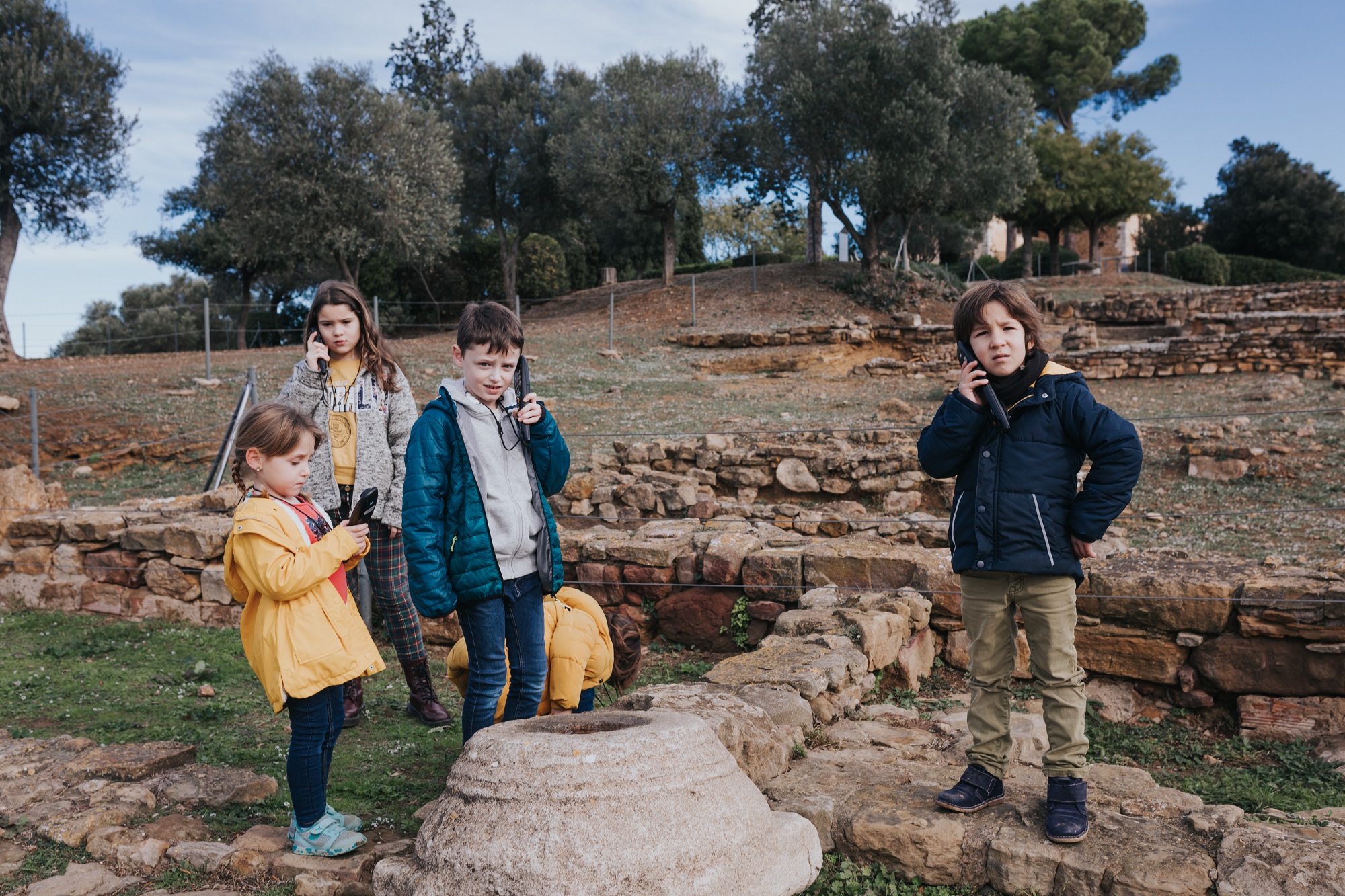 Quatre infants escoltant una audioguia en un jaciment iber. 