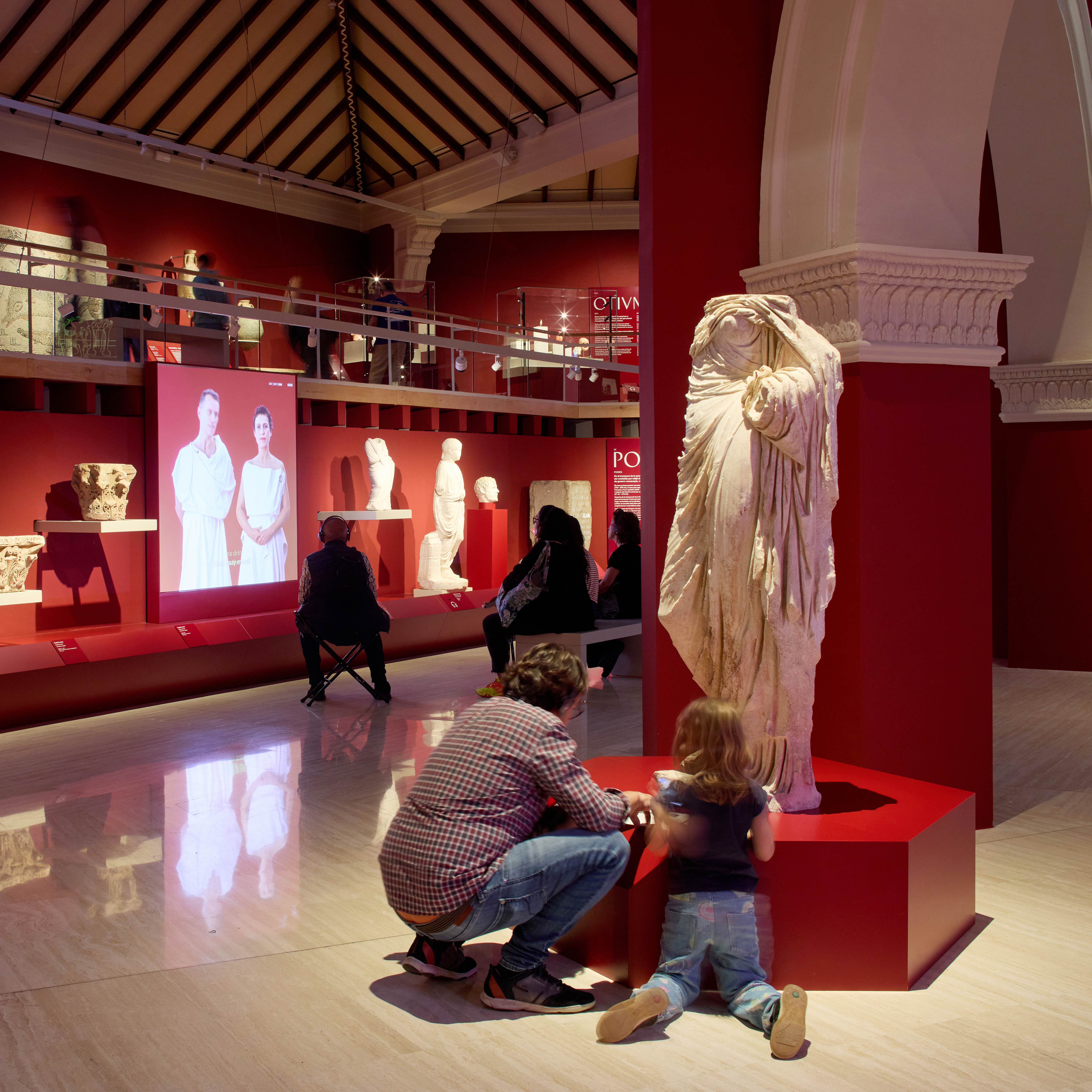 Un home i una nena mirant de prop una escultura romana
