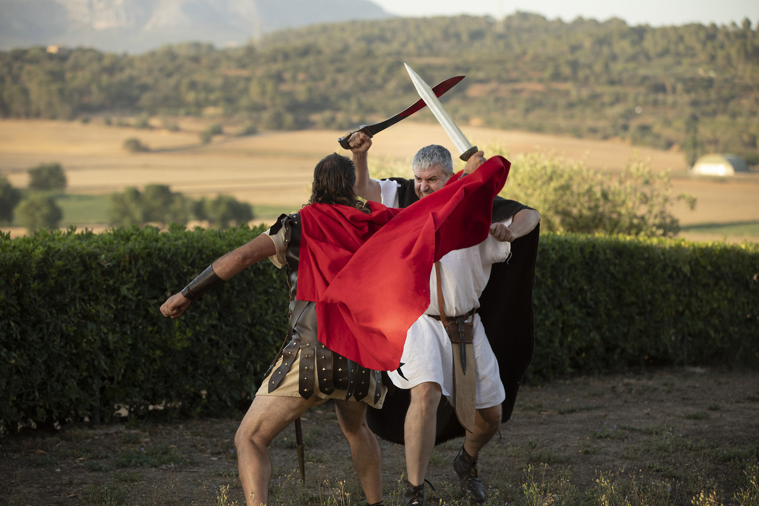 Dos actors vestits d'època iber i romana fent una visita teatral.