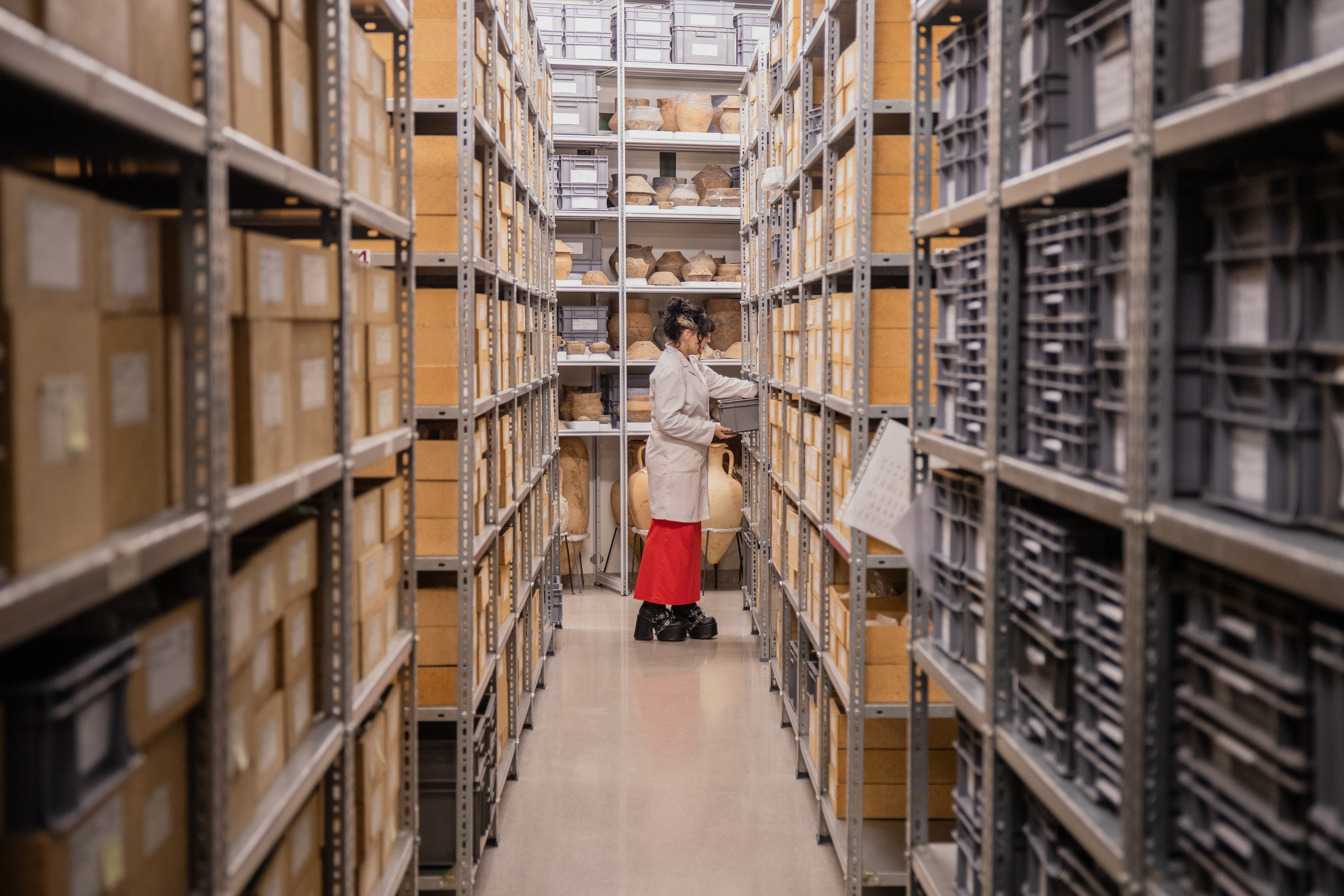 Una noia en un magatzem entre passadissos de caixes.